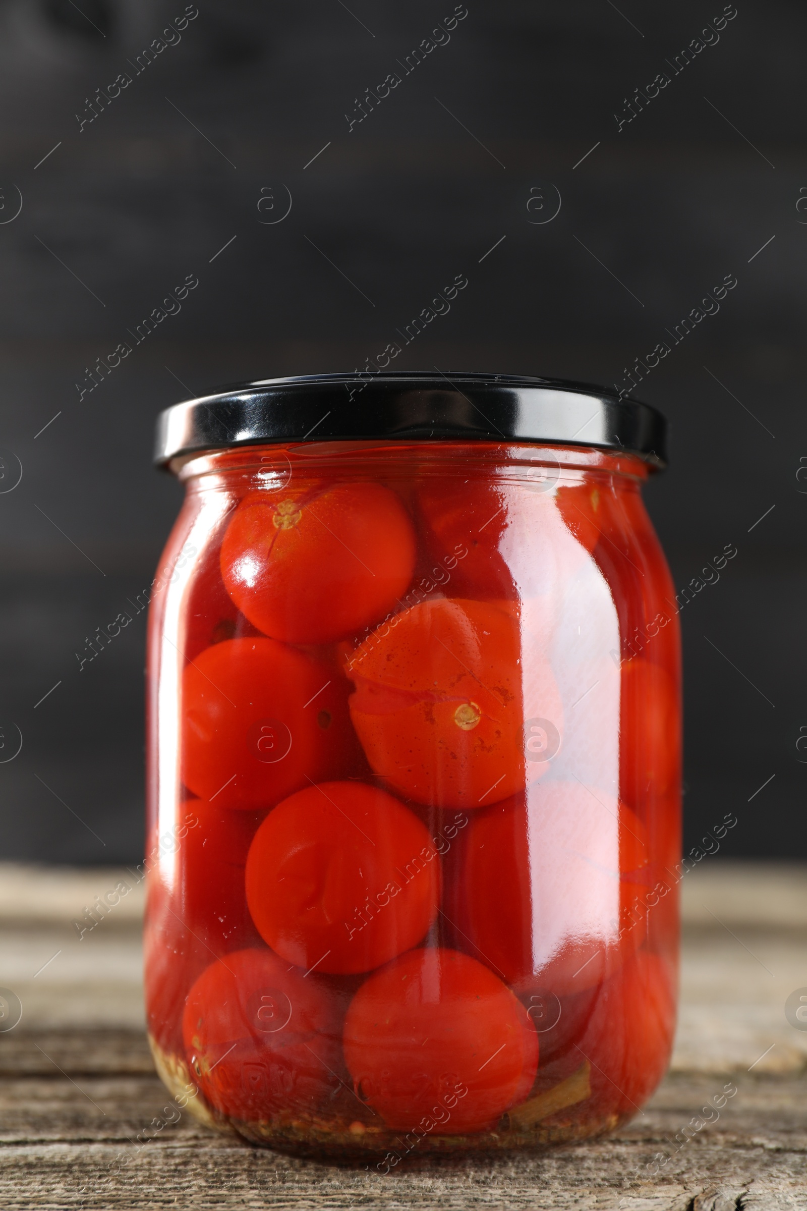 Photo of Tasty pickled tomatoes in jar on wooden table