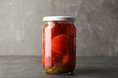 Tasty pickled tomatoes in jar on grey table