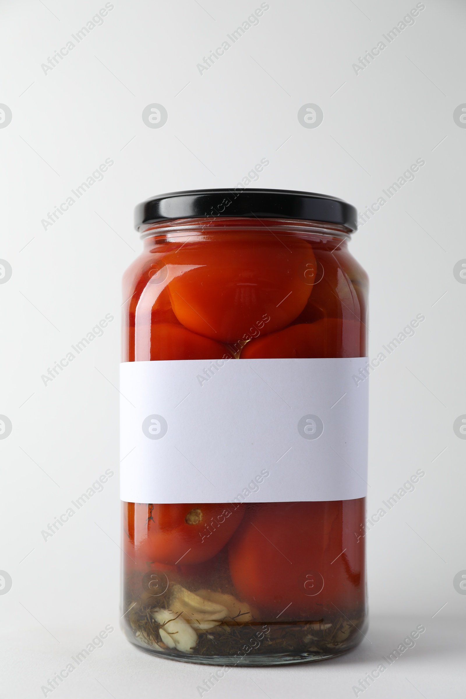 Photo of Tasty pickled tomatoes in jar on light background