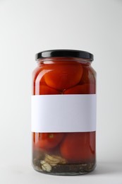 Photo of Tasty pickled tomatoes in jar on light background