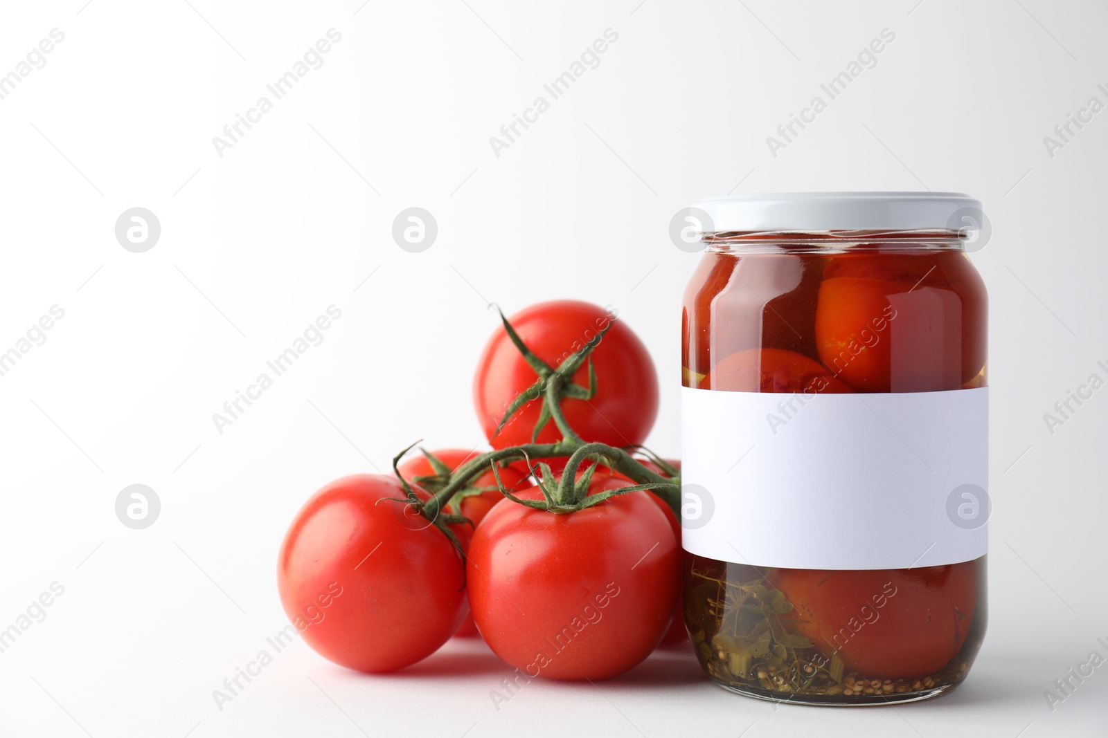 Photo of Tasty pickled tomatoes in jar and vegetables on light background. Space for text