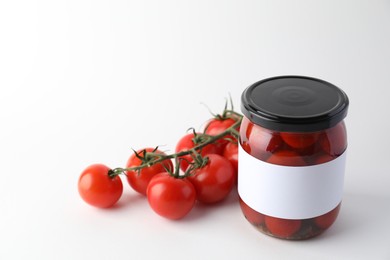 Tasty pickled tomatoes in jar and vegetables on light background. Space for text
