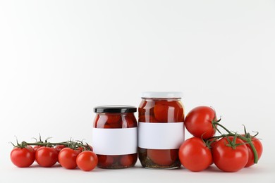 Photo of Tasty pickled tomatoes in jars and vegetables on light background. Space for text