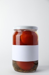 Tasty pickled tomatoes in jar on light background