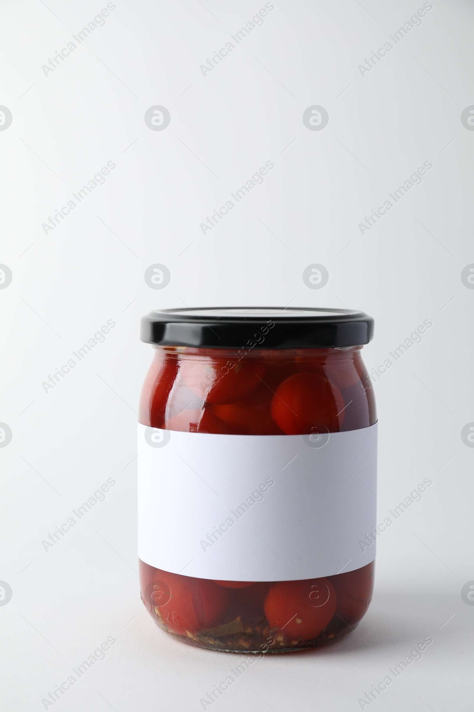 Photo of Tasty pickled tomatoes in jar on light background