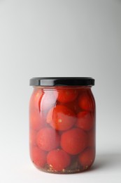 Tasty pickled tomatoes in jar on light grey background