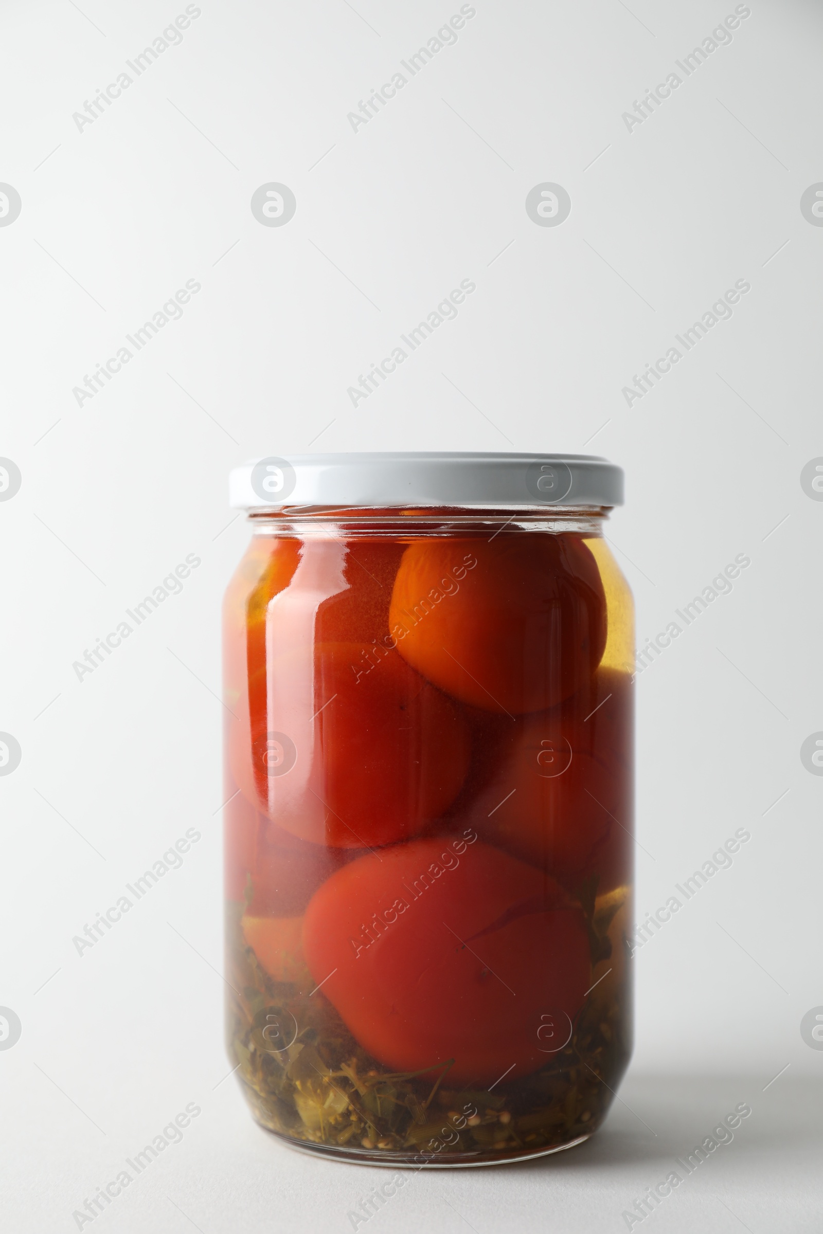 Photo of Tasty pickled tomatoes in jar on light grey background