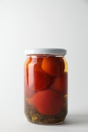 Tasty pickled tomatoes in jar on light grey background