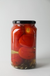 Tasty pickled tomatoes in jar on light grey background