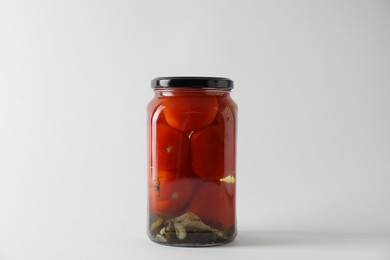 Photo of Tasty pickled tomatoes in jar on light grey background