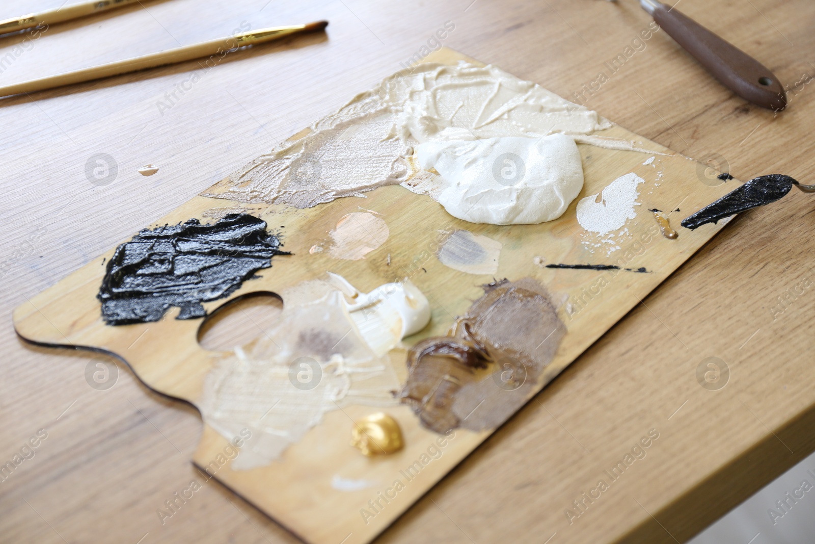 Photo of Palette with paints on wooden table, closeup