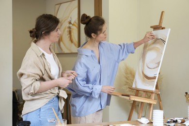 Photo of Artist teaching her student to paint in studio