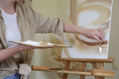 Woman with palette drawing picture in studio, closeup