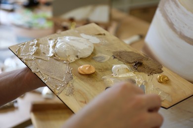 Photo of Woman with wooden palette in drawing studio, closeup