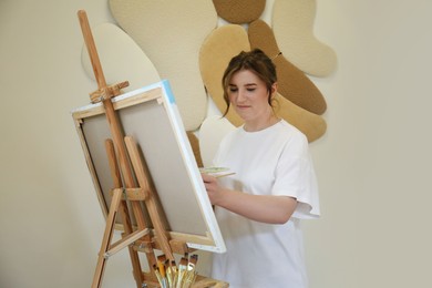 Woman drawing on easel with canvas in studio