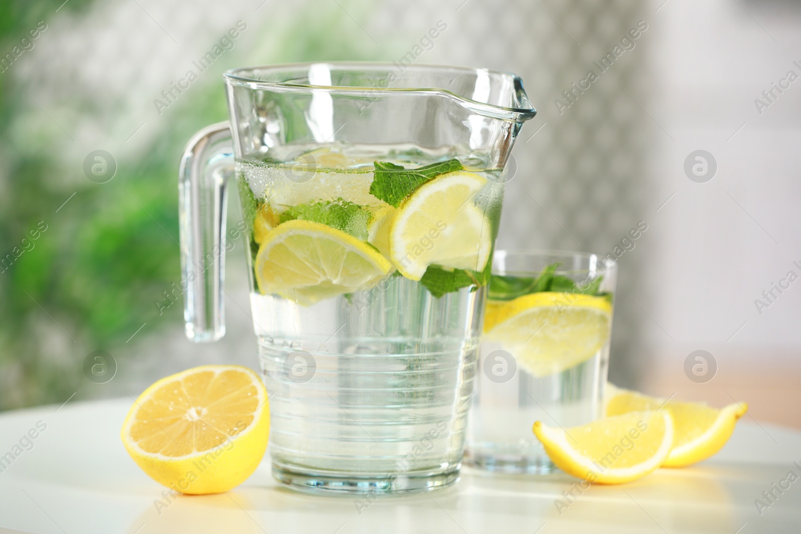 Photo of Refreshing lemonade with mint in jug and glass on white table, closeup