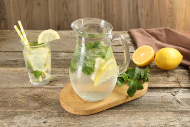 Refreshing lemonade with mint in jug and glass on wooden table