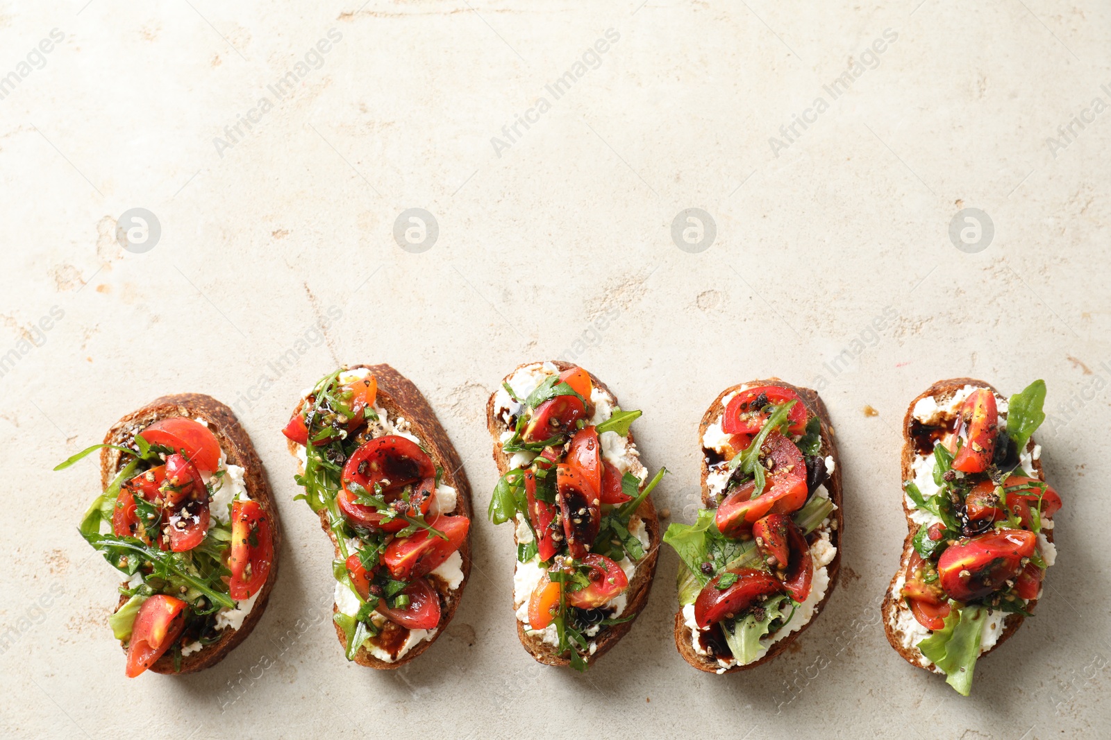 Photo of Delicious bruschettas with ricotta cheese, tomatoes and arugula on light textured table, flat lay. Space for text