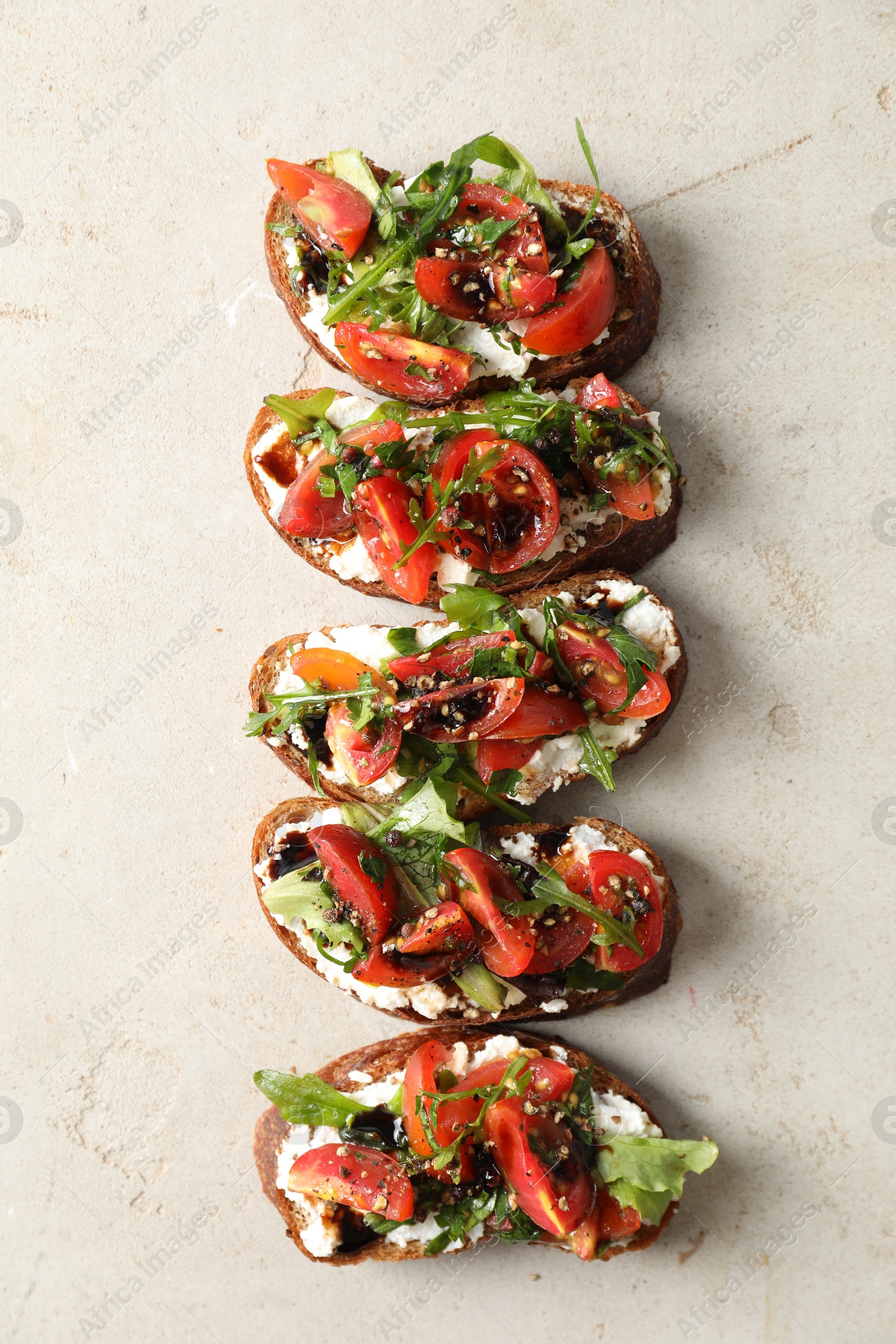 Photo of Delicious bruschettas with ricotta cheese, tomatoes and arugula on light textured table, flat lay