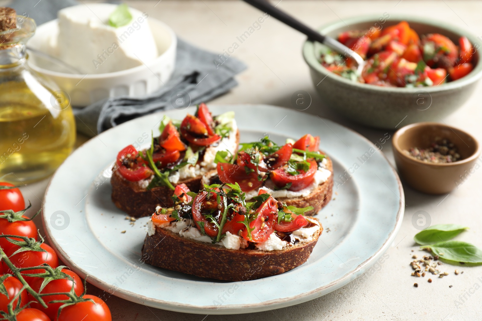 Photo of Delicious bruschettas with ricotta cheese, tomatoes, and arugula on light table, closeup