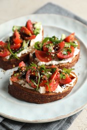 Delicious bruschettas with ricotta cheese, tomatoes and arugula on light table, closeup