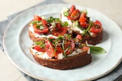 Delicious bruschettas with ricotta cheese, tomatoes and arugula on light table, closeup