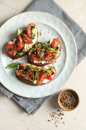 Delicious bruschettas with ricotta cheese, tomatoes, arugula and peppercorns on light table, flat lay