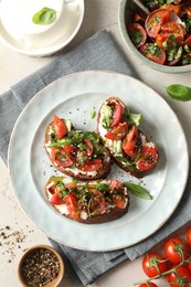 Delicious bruschettas with ricotta cheese, tomatoes, arugula, salad and peppercorns on light table, flat lay