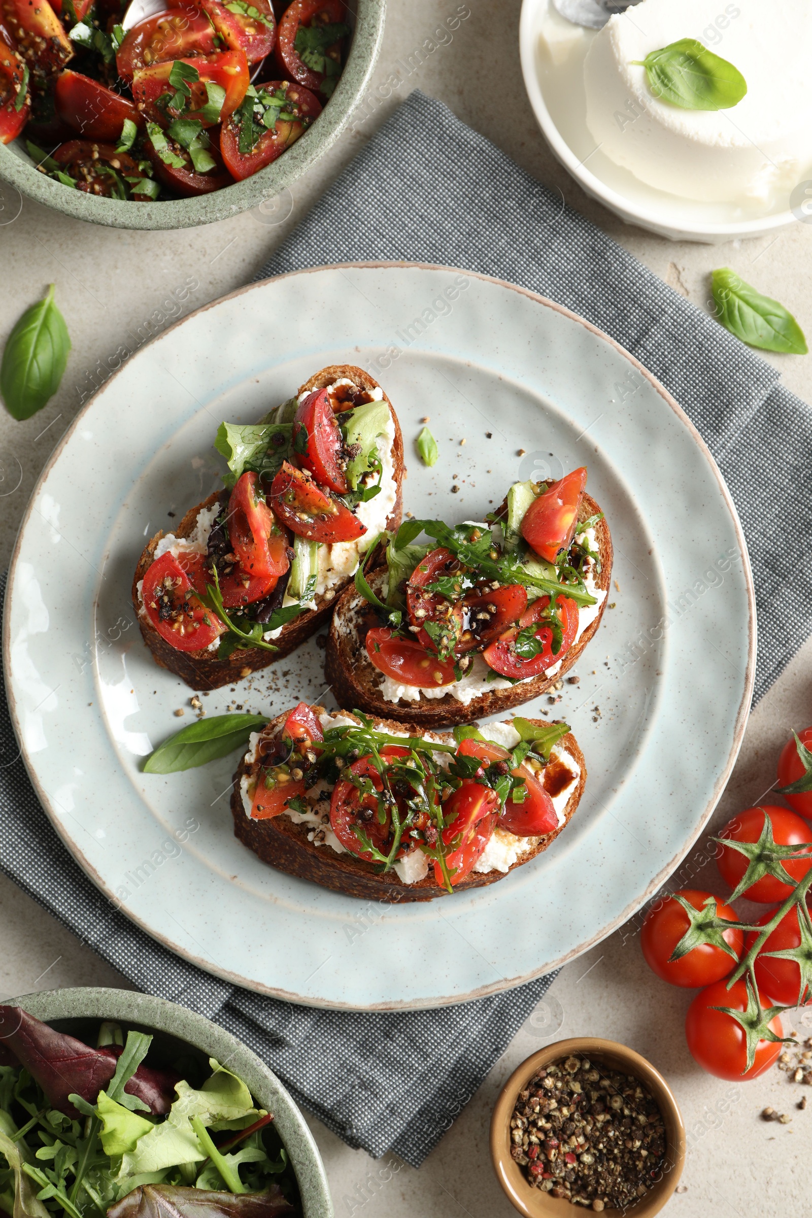 Photo of Delicious bruschettas with ricotta cheese, tomatoes, arugula, salad and peppercorns on light table, flat lay