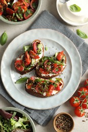 Delicious bruschettas with ricotta cheese, tomatoes, arugula, salad and peppercorns on light table, flat lay