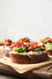 Delicious ricotta bruschettas with tomatoes and arugula on wooden table, closeup. Space for text