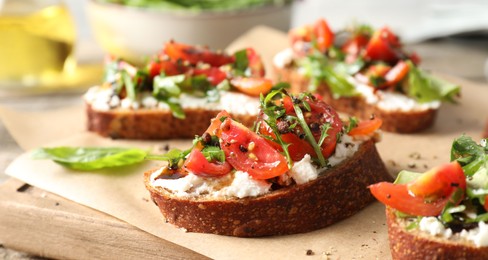 Delicious ricotta bruschettas with tomatoes and arugula on table, closeup