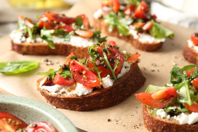 Delicious ricotta bruschettas with tomatoes and arugula on parchment, closeup