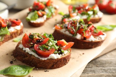 Delicious ricotta bruschettas with tomatoes, arugula and basil on wooden table, closeup