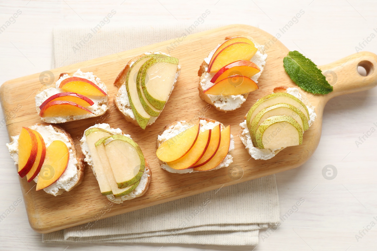 Photo of Delicious ricotta bruschettas with pears and apricots on white wooden table, top view