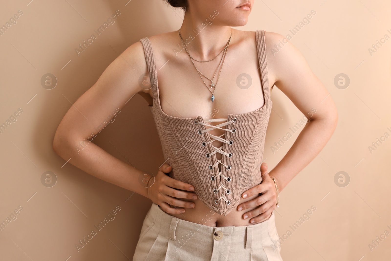 Photo of Woman in stylish corset near beige wall, closeup