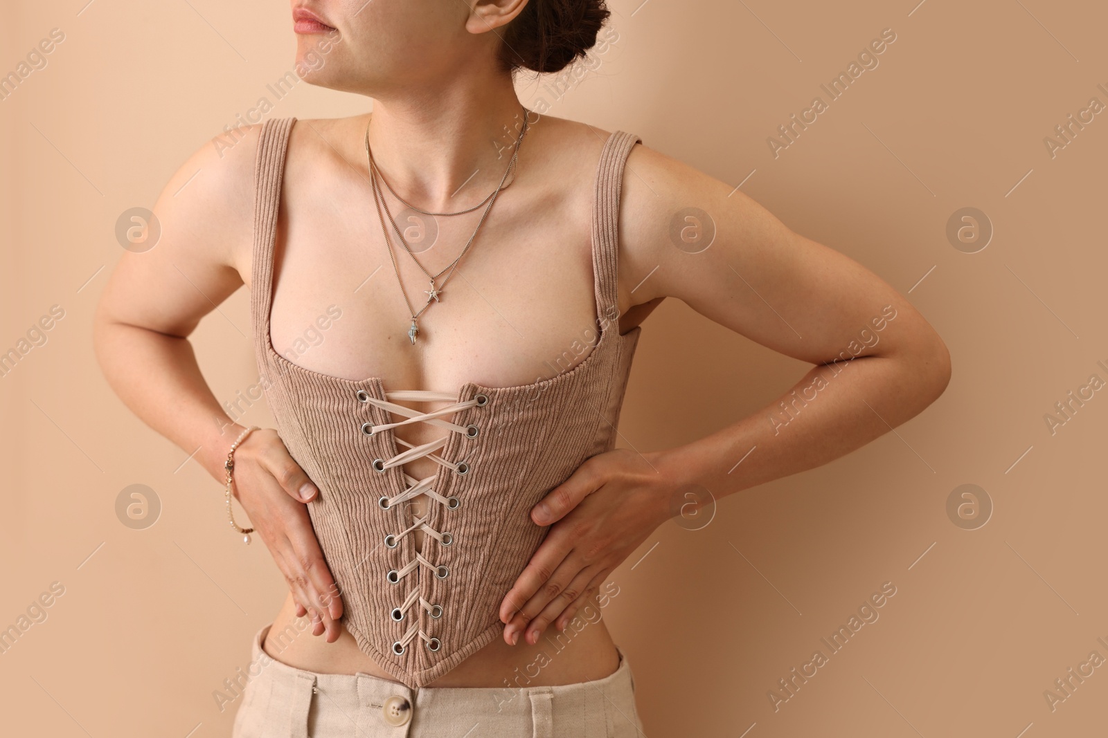 Photo of Woman in stylish corset near beige wall, closeup