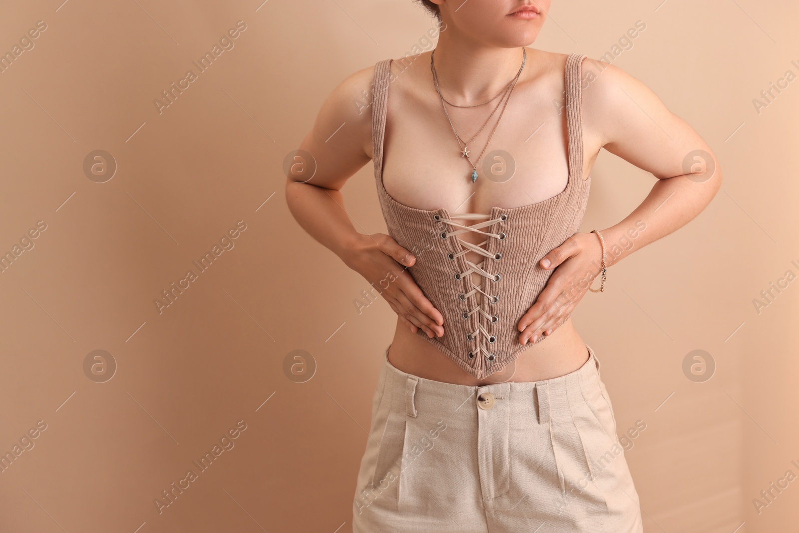 Photo of Woman in stylish corset near beige wall, closeup. Space for text