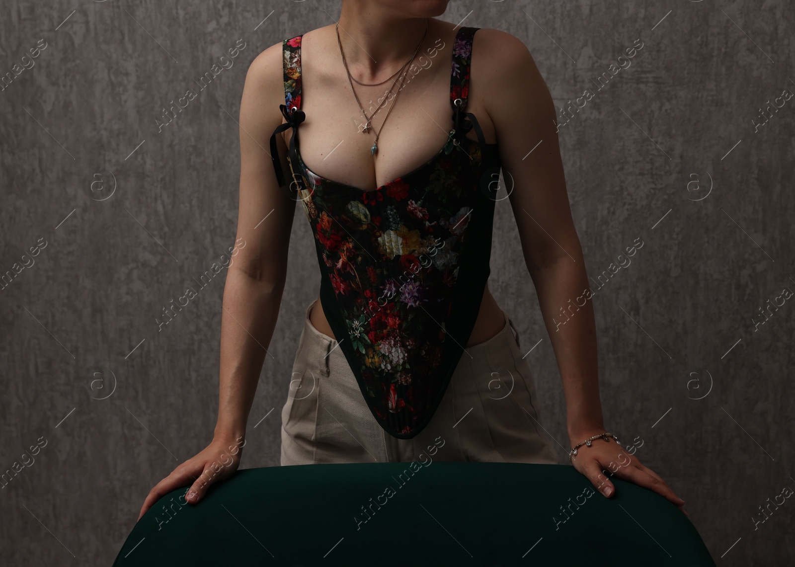 Photo of Woman in stylish corset near grey wall, closeup