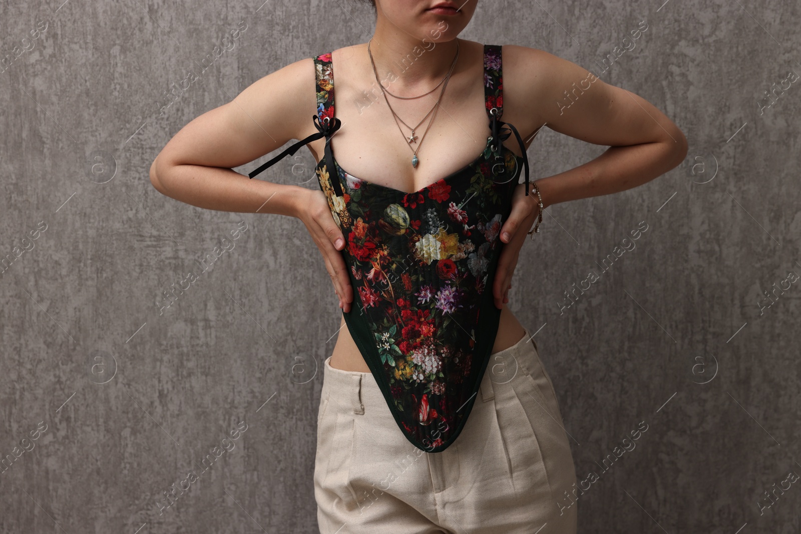 Photo of Woman in stylish corset near grey wall, closeup