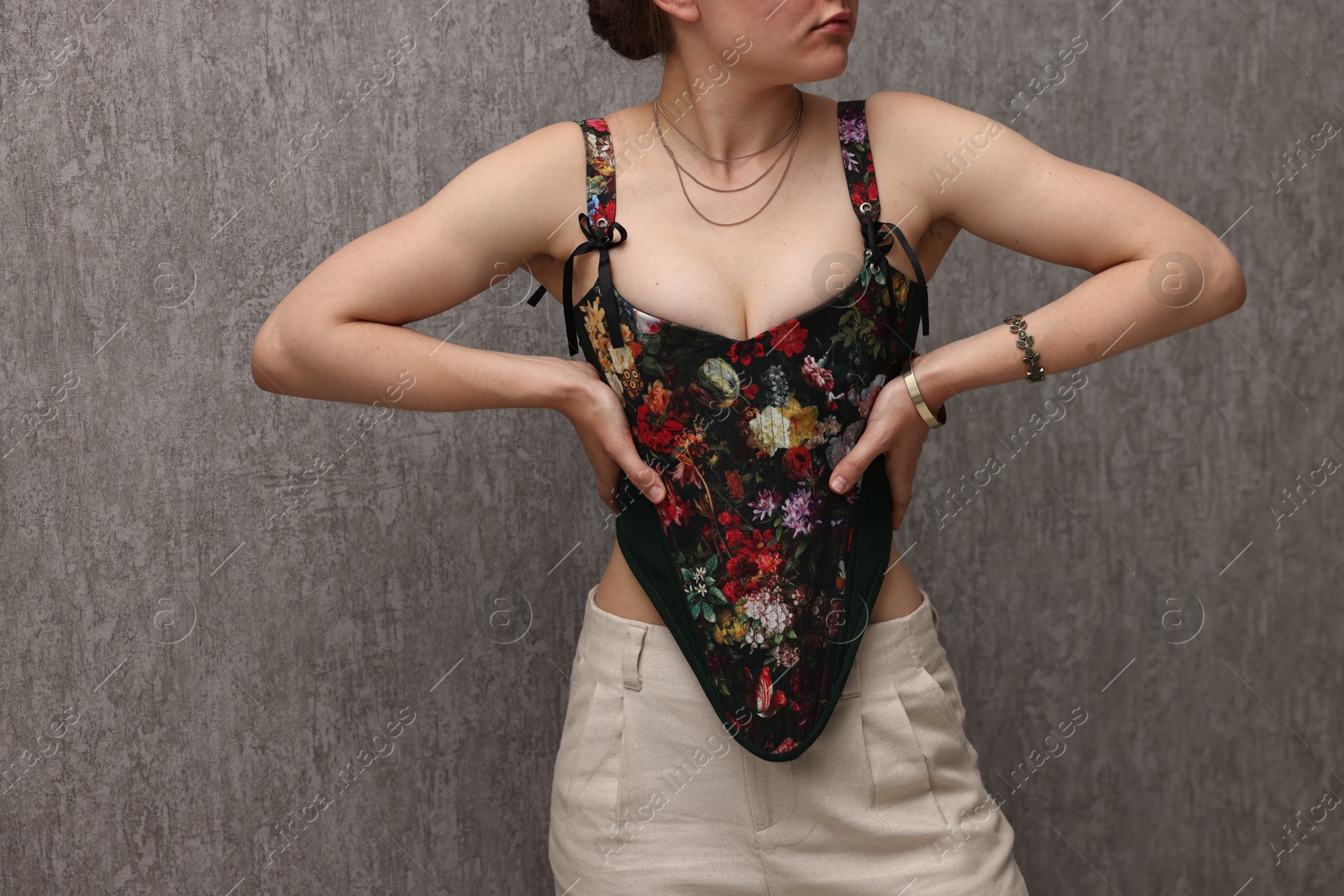 Photo of Woman in stylish corset near grey wall, closeup