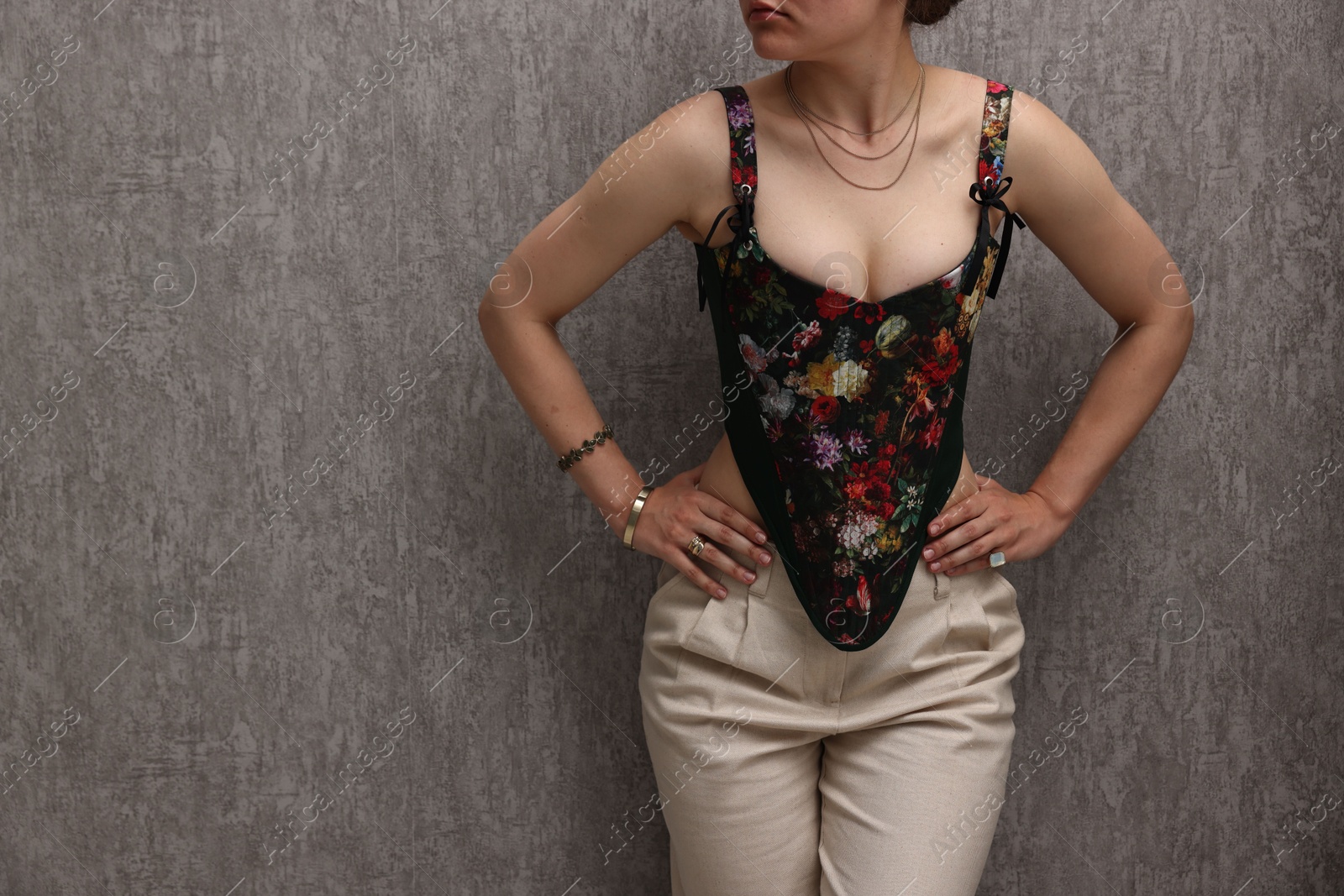 Photo of Woman in stylish corset near grey wall, closeup. Space for text