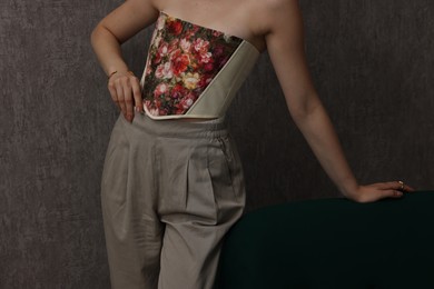 Photo of Woman in stylish corset near grey wall, closeup