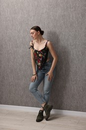 Photo of Beautiful young woman in stylish corset near grey wall