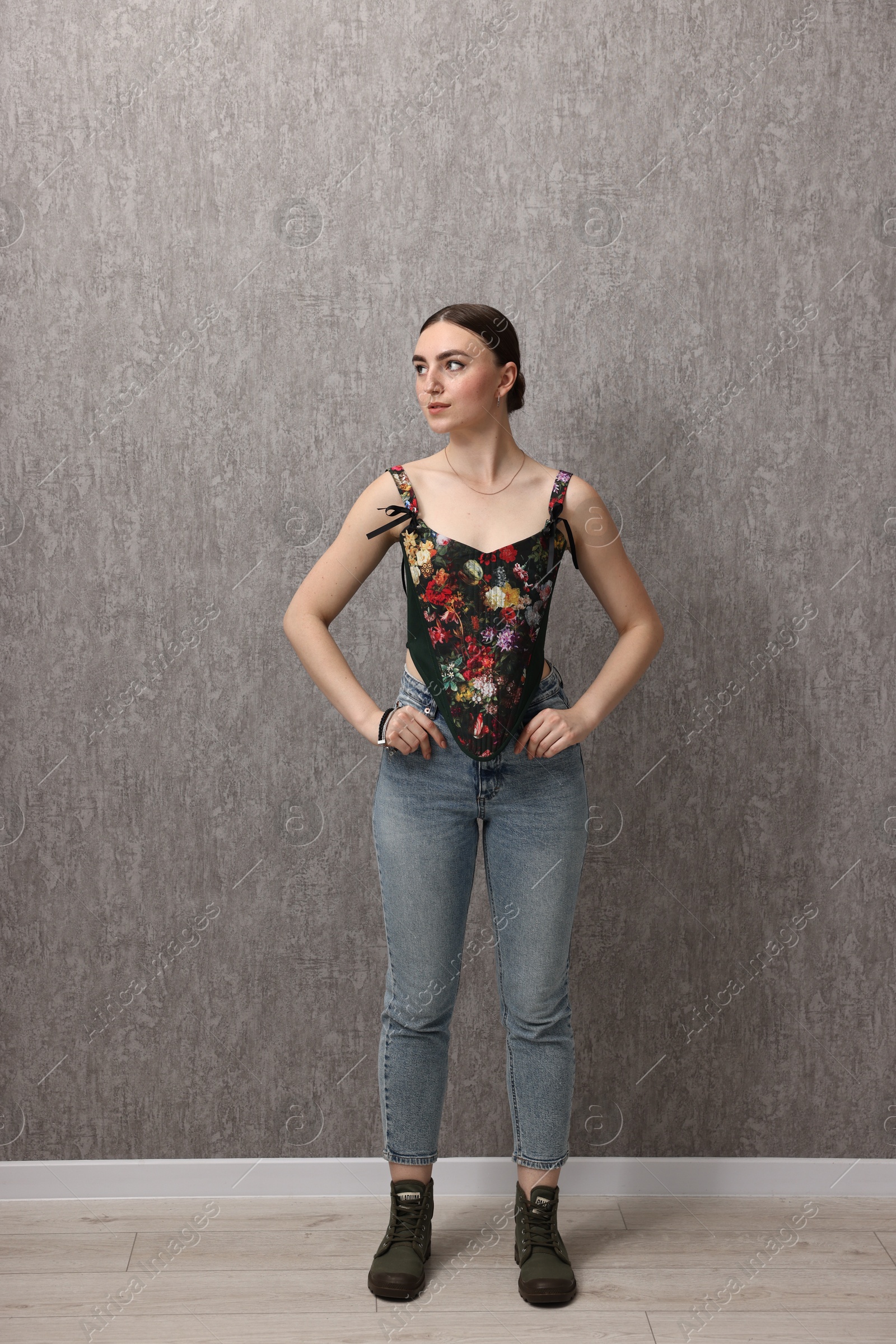 Photo of Beautiful young woman in stylish corset near grey wall