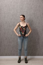 Photo of Beautiful young woman in stylish corset near grey wall