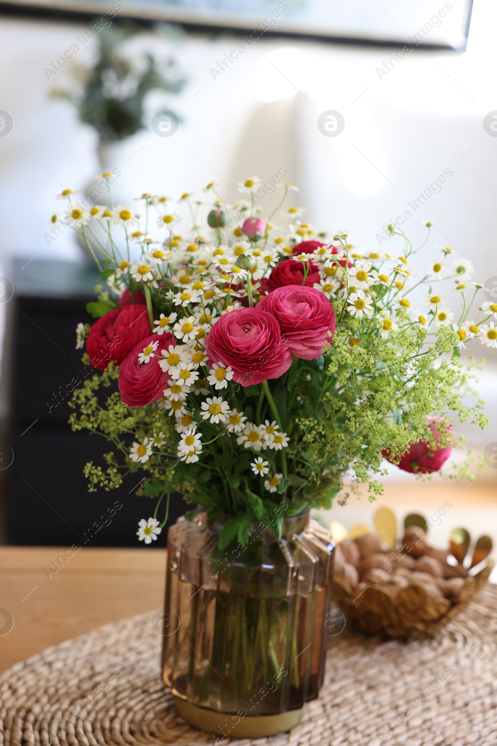 Photo of Beautiful ranunculus flowers and chamomiles in vase on table indoors