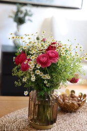 Beautiful ranunculus flowers and chamomiles in vase on table indoors