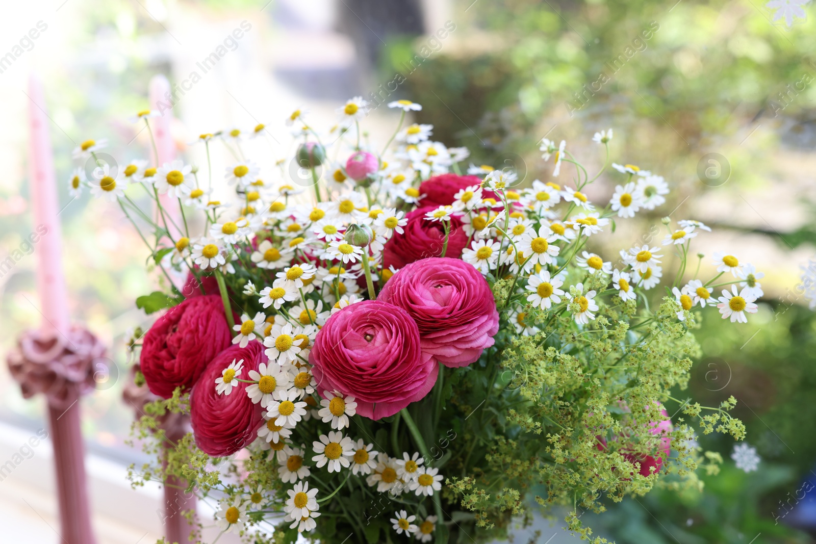 Photo of Beautiful ranunculus flowers and chamomiles near window indoors