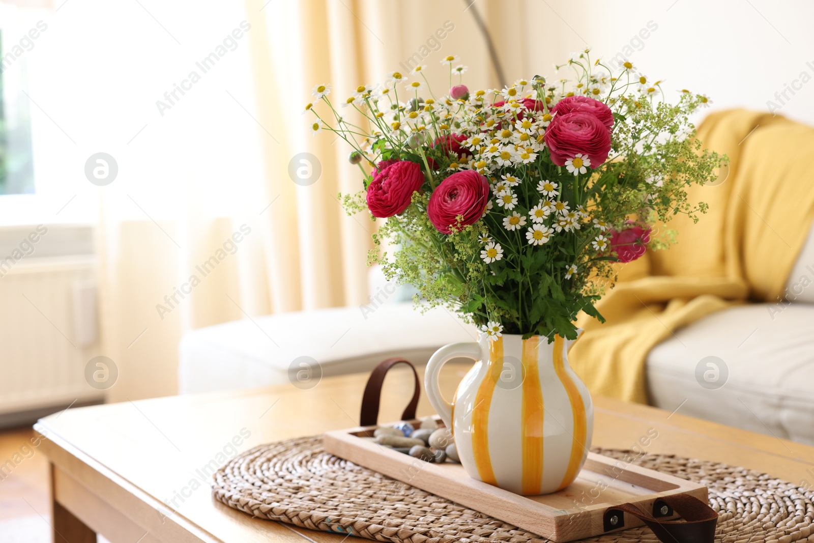 Photo of Beautiful ranunculus flowers and chamomiles in vase on table indoors, space for text